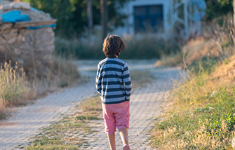 Child worker walking barefoot down path