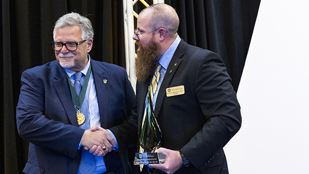 two men shake hands at an award ceremony for ASSP volunteers