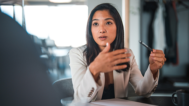 A woman wearing a white suit sits at a table