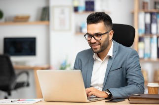 Safety professional with glasses doing OSHA recordkeeping on the computer and smiling