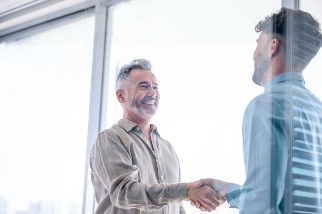 Two men shaking hands in an office and discussing how to establish a safety career